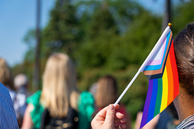 A picture of a hand holding a pride flag in a parade