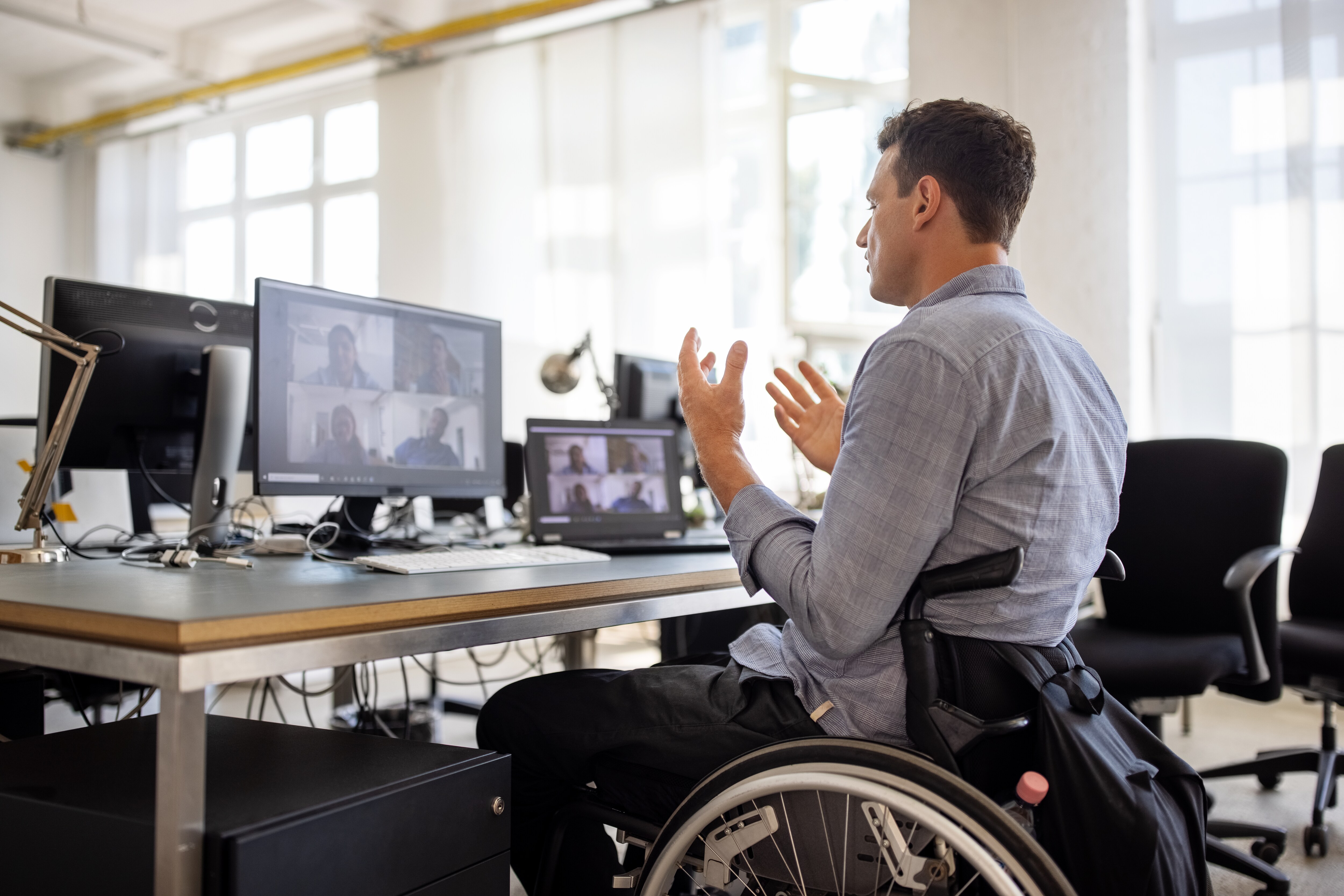 One man in a wheelchair facing a computer screen on a video call.