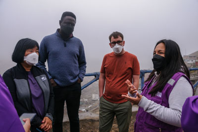 Four people wearing masks stand outside talking.