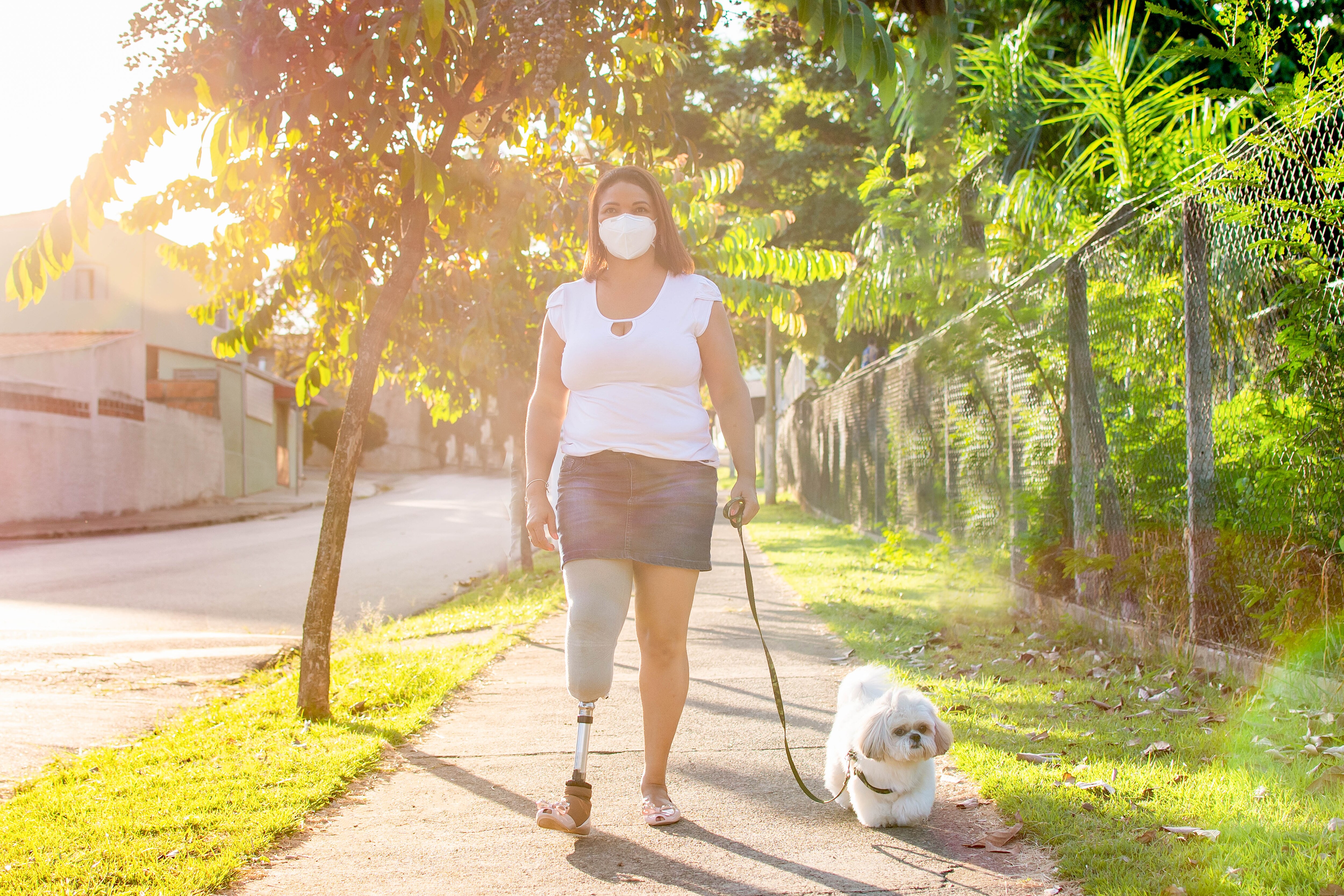 Amputated woman walking dog wearing a 3M particulate respirator.