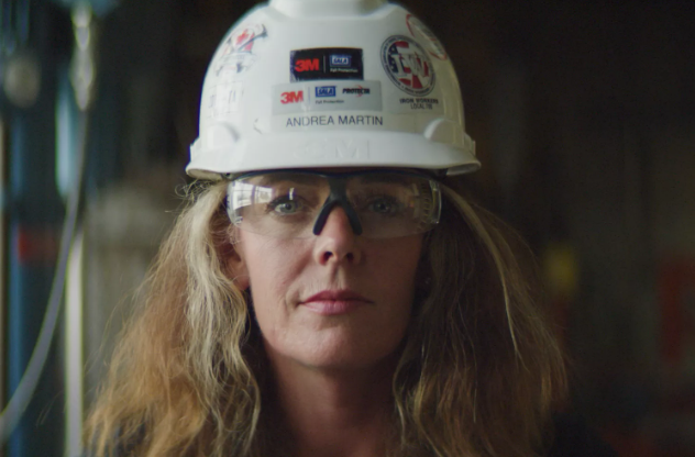 A woman in a hard hat looking straight forward.